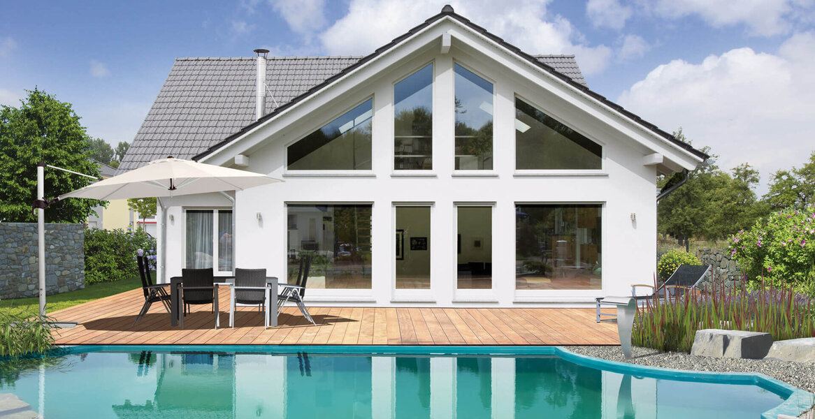 Fingerhut Einfamilienhaus dunkles Satteldach weißer Putz grosse Glasfront Terrasse Terrassenmöbel Sonnenschirm Pool 
