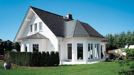 Fingerhut Einfamilienhaus mit schwarzem Satteldach hell verputzt Erker Terrasse 