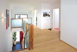 Galerie heller Holzfußboden weiße Wände Treppe Treppengeländer aus Holz und Glas 