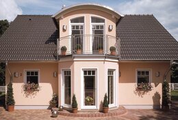 Fingerhut Einfamilienhaus dunkles Satteldach lachsfarbener Putz mit Gaube und Erker weiße Fenster 