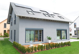 Fingerhut Einfamilienhaus schwarzes Satteldach grau verputzt bodentiefe grau Terrassenfenster Holzterrasse Dachfenster 