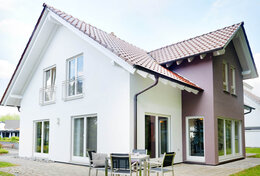 Fingerhut Einfamilienhaus braunes Satteldach weiß verputzt teilweise farblich braun abgesetzt weiße Fenster Terrasse Gartenmöbel 